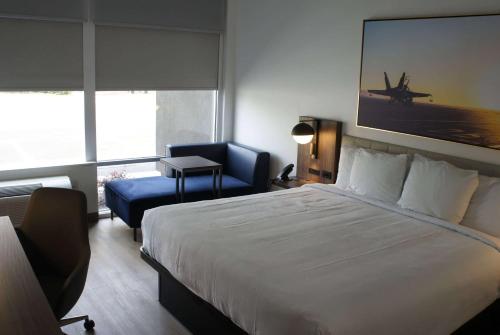 a bedroom with a large bed and a blue chair at La Quinta Inn & Suites by Wyndham Manchester - Arnold AFB in Manchester