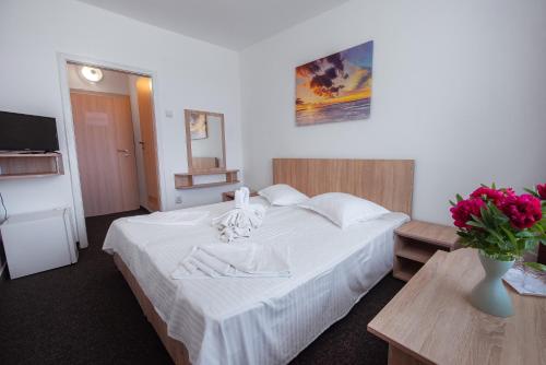 - une chambre avec un lit blanc et un vase de fleurs dans l'établissement Hotel Nadia Eforie Nord, à Eforie Nord