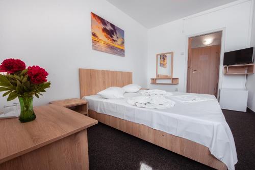 Un dormitorio con una cama con un jarrón de flores. en Hotel Nadia Eforie Nord, en Eforie Nord