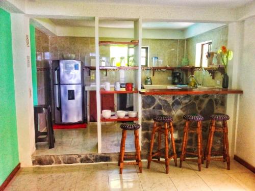 a kitchen with a bar with stools and a refrigerator at Windy View Guest House in Providencia