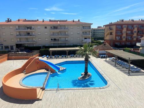 een zwembad met een glijbaan en een palmboom bij Apartamentos familiares Sa Gavina Gaudí in L'Estartit