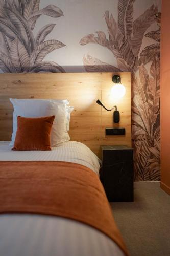 a bedroom with a bed with a wooden headboard and a lamp at Quintessia in Orvault