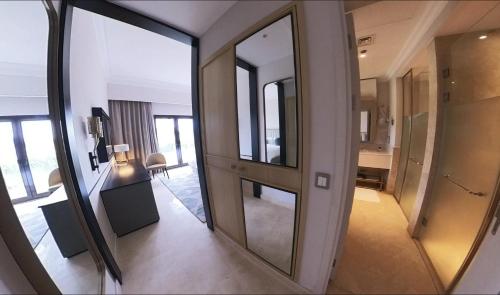 1 Bedroom Suite @ The address Golf Marassi Resort في العلمين: ممر مع مرآة كبيرة في غرفة الفندق