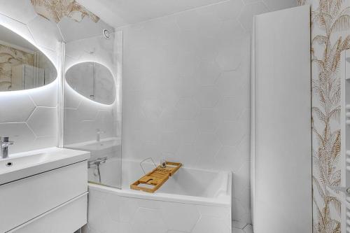 La salle de bains blanche est pourvue d'une baignoire et d'un lavabo. dans l'établissement Le Jolimont T4 et vues spectaculaires sur la ville, à Toulouse