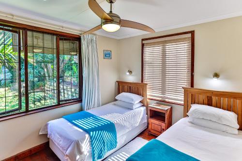 two beds in a room with windows at Zuider Zee Guest House in Ballito