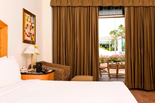 a hotel room with a bed and a chair and a window at Le Royal Meridien Chennai in Chennai