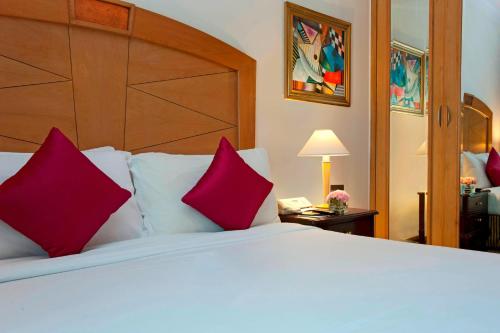 1 dormitorio con 1 cama blanca grande con almohadas rojas en Le Royal Meridien Chennai en Chennai