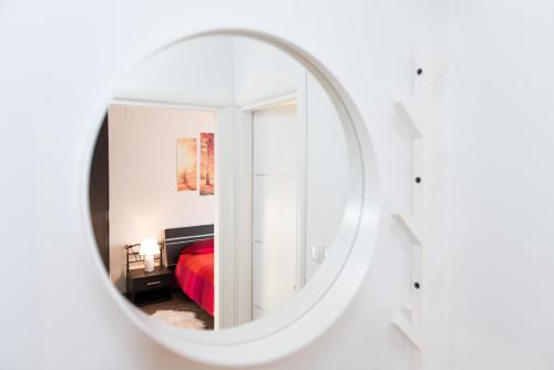 a mirror in a white room with a red bed at Emmy i Alice in Josipdol