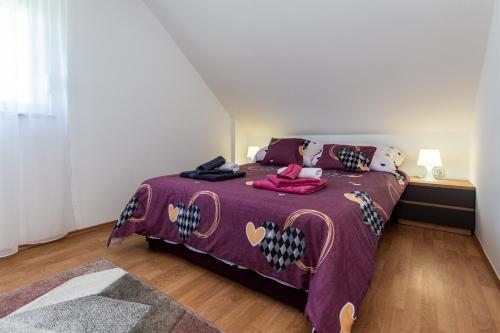 a bedroom with a bed with a purple comforter at Emmy i Alice in Josipdol