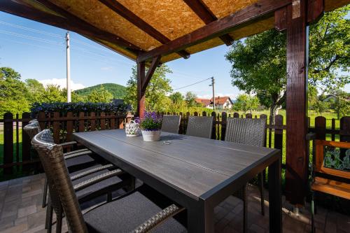 a wooden table and chairs on a patio with a fence at Emmy i Alice in Josipdol