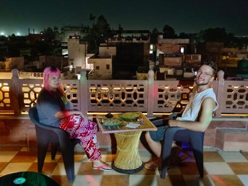 un uomo e una donna seduti a un tavolo sul balcone di Hotel India inn ad Agra
