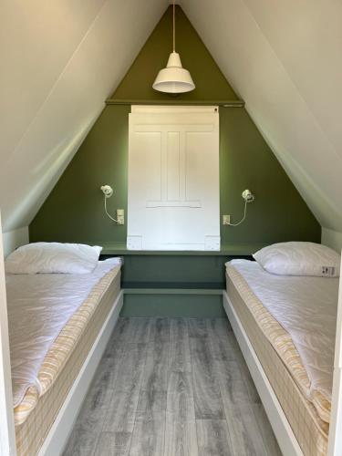two beds in a attic room with green walls at Løgstør Camping in Løgstør