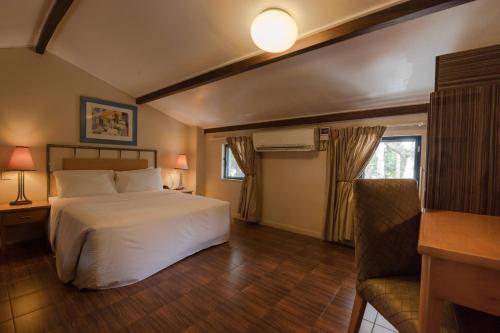 Protea Hotel by Marriott Dar es Salaam Oyster Bay في دار السلام: غرفة نوم بسرير ابيض واريكة