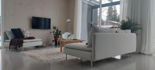 - un salon avec deux canapés et une télévision dans l'établissement New Villa w/sauna, jacuzzi &wifi, à Hämeenlinna