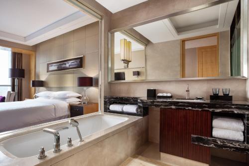 a hotel bathroom with a tub and a bed at Sheraton Zhenjiang Hotel in Zhenjiang