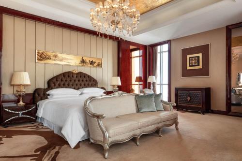 a bedroom with a bed and a chair and a chandelier at Sheraton Zhenjiang Hotel in Zhenjiang