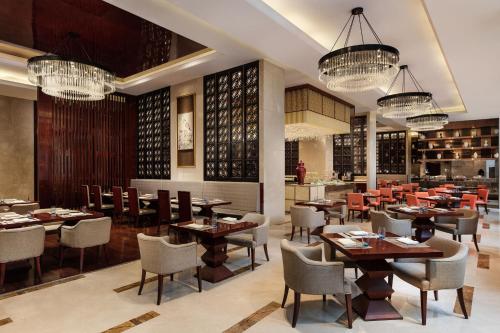 a restaurant with tables and chairs and chandeliers at Sheraton Zhenjiang Hotel in Zhenjiang