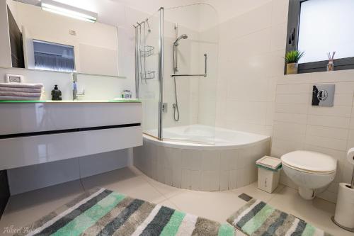 a bathroom with a tub and a toilet and a shower at Iwo's - וילה איוו - מדהימה ויוקרתית עם בריכה פרטית ונוף מטורף לכנרת in Migdal