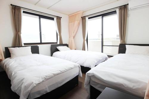 2 camas en una habitación con 2 ventanas en 志摩の別荘 en Shima
