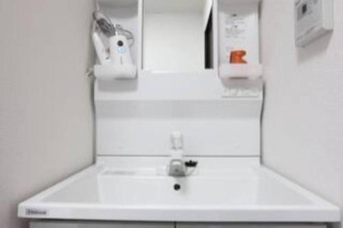 La salle de bains blanche est pourvue d'un lavabo et d'un miroir. dans l'établissement 志摩の別荘, à Shima