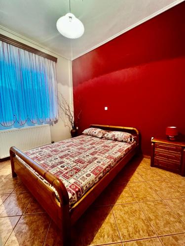 een slaapkamer met een bed met een rode muur bij Kolovos House in Karyes