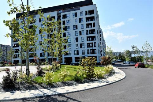 a building with a garden in front of a street at Oak Apartment lovely one bedroom apartment at Columna Residence near Vivo mall in Cluj-Napoca