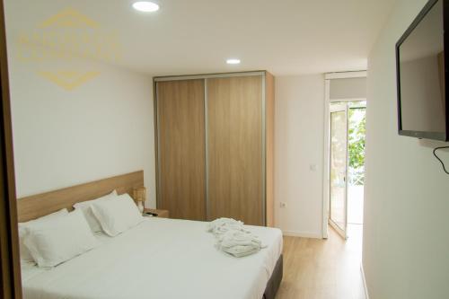 a bedroom with a white bed and a television at Refúgio da Suite 5 in Pinhão