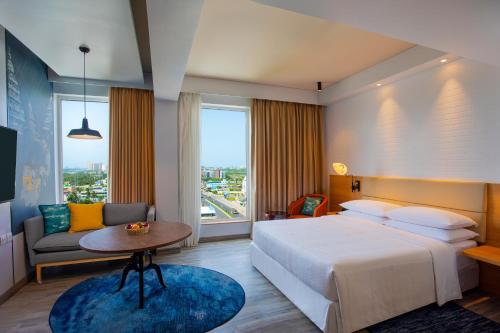 チェンナイにあるFour Points by Sheraton Chennai OMRのベッド、テーブル、ソファが備わるホテルルームです。
