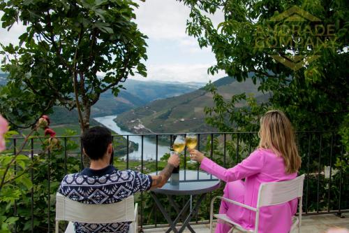 a man and a woman sitting at a table with a glass of wine at Refúgio da Suite 5 in Pinhão