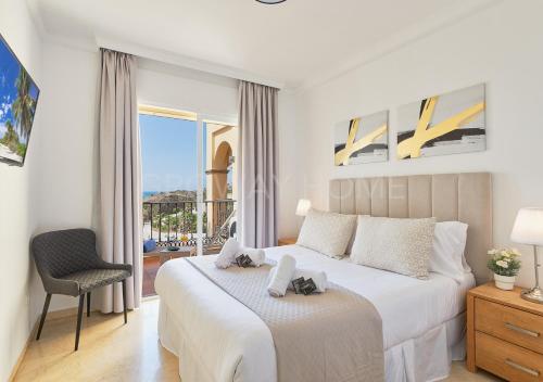 a white bedroom with a bed and a balcony at Marina XI Lovely apartment inside Wyndham Resort in Mijas Costa