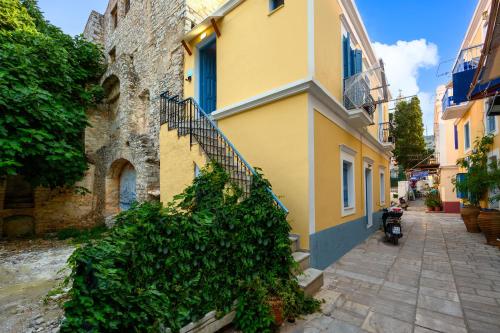a yellow building with a staircase next to a street at Ritzi Apartment in Symi