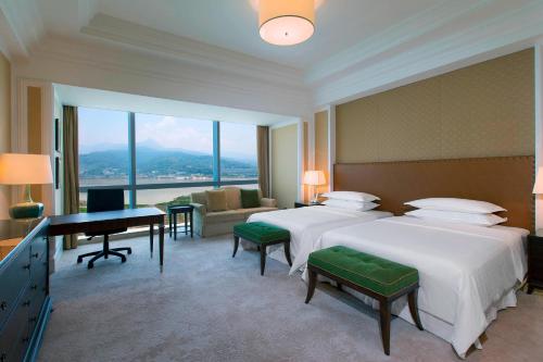 a hotel room with two beds and a desk at Sheraton Fuzhou Hotel in Fuzhou