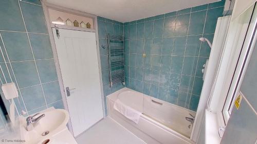a bathroom with a tub and a toilet and a sink at 36 Strawberry Hill, Tolroy Manor in Hayle