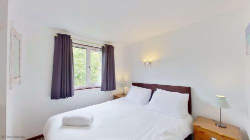 a bedroom with a white bed and a window at 36 Strawberry Hill, Tolroy Manor in Hayle