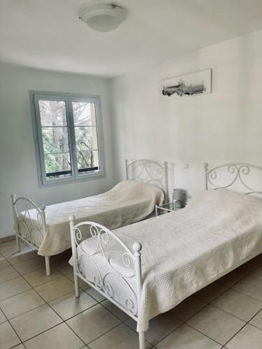 2 łóżka w białym pokoju z oknem w obiekcie Villas A Torra w mieście Patrimonio