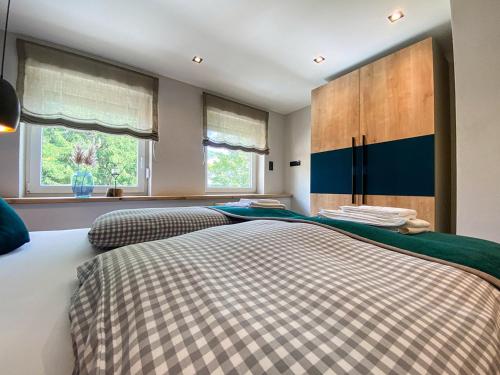 two beds in a bedroom with two windows at Bergidyll in Oberstaufen