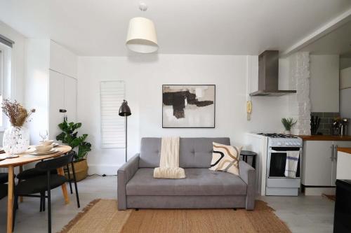 W London apt for 4. Open plan kitchen/living room في لندن: غرفة معيشة مع أريكة رمادية وطاولة