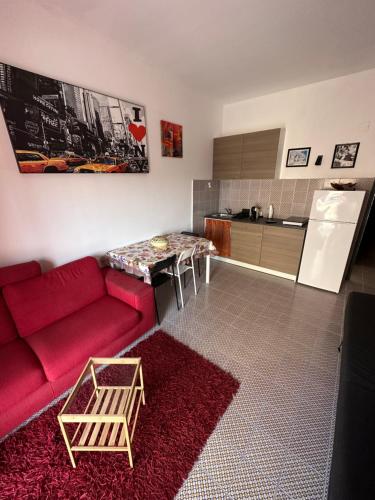 a living room with a red couch and a kitchen at Serena Holiday Home Calatabiano in Calatabiano