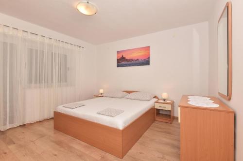 a white bedroom with a bed and a table at Apartments Vjeko in Makarska