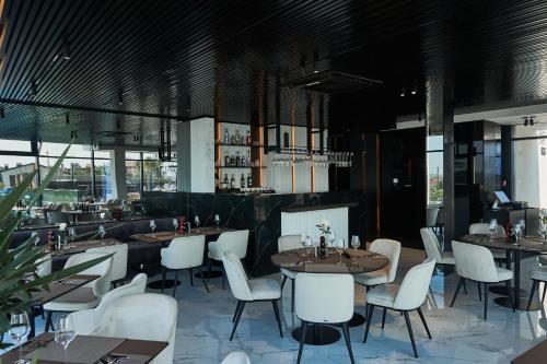 a restaurant with tables and white chairs and windows at WHITE HILLS HOTEL spa&sport in Uzhhorod