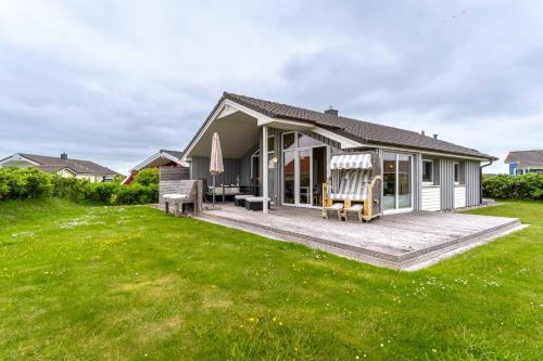 a house with a deck and a lawn at Nordseenest am Deich in Wesselburenerkoog
