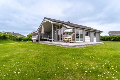 a small house with a large green yard at Nordseenest am Deich in Wesselburenerkoog