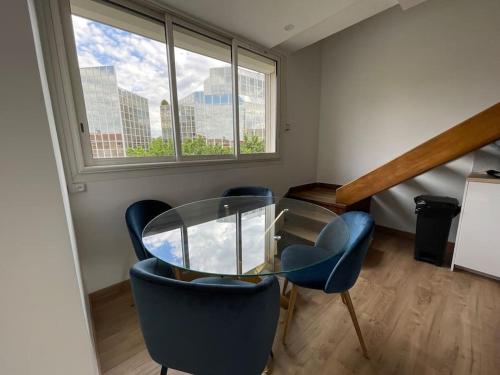 une salle à manger avec une table en verre et des chaises bleues dans l'établissement Le Compans: exceptionnel T5 en berges du Canal, à Toulouse