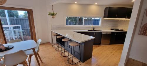 a kitchen with a counter and a island with stools at Live - Play - Stay - East Geelong in Geelong