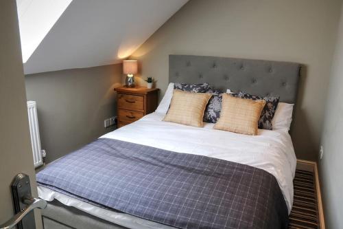 a bedroom with a large bed with a gray headboard at Queensgate Holiday Cottage Beverley with Parking in Beverley