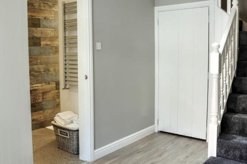 a hallway with a white door and stairs at Queensgate Holiday Cottage Beverley with Parking in Beverley
