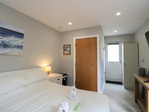 a bedroom with a white bed and a wooden door at Modern Room with Private Outdoor space Pass The Keys in Gosforth