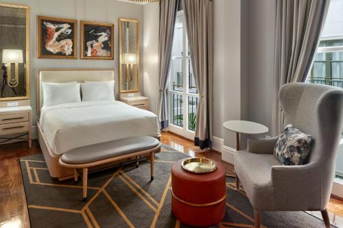 une chambre d'hôtel avec un lit et une chaise dans l'établissement The Tremont House, Galveston, a Tribute Portfolio Hotel, à Galveston
