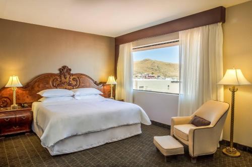 - une chambre avec un lit, une fenêtre et une chaise dans l'établissement Sheraton Chihuahua Soberano, à Chihuahua