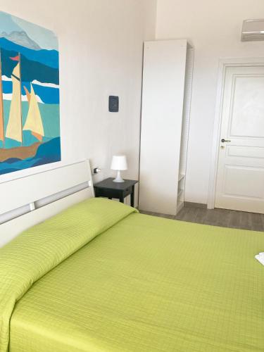 a bedroom with a green bed with a painting on the wall at La Meriggia B&B in Pisciotta